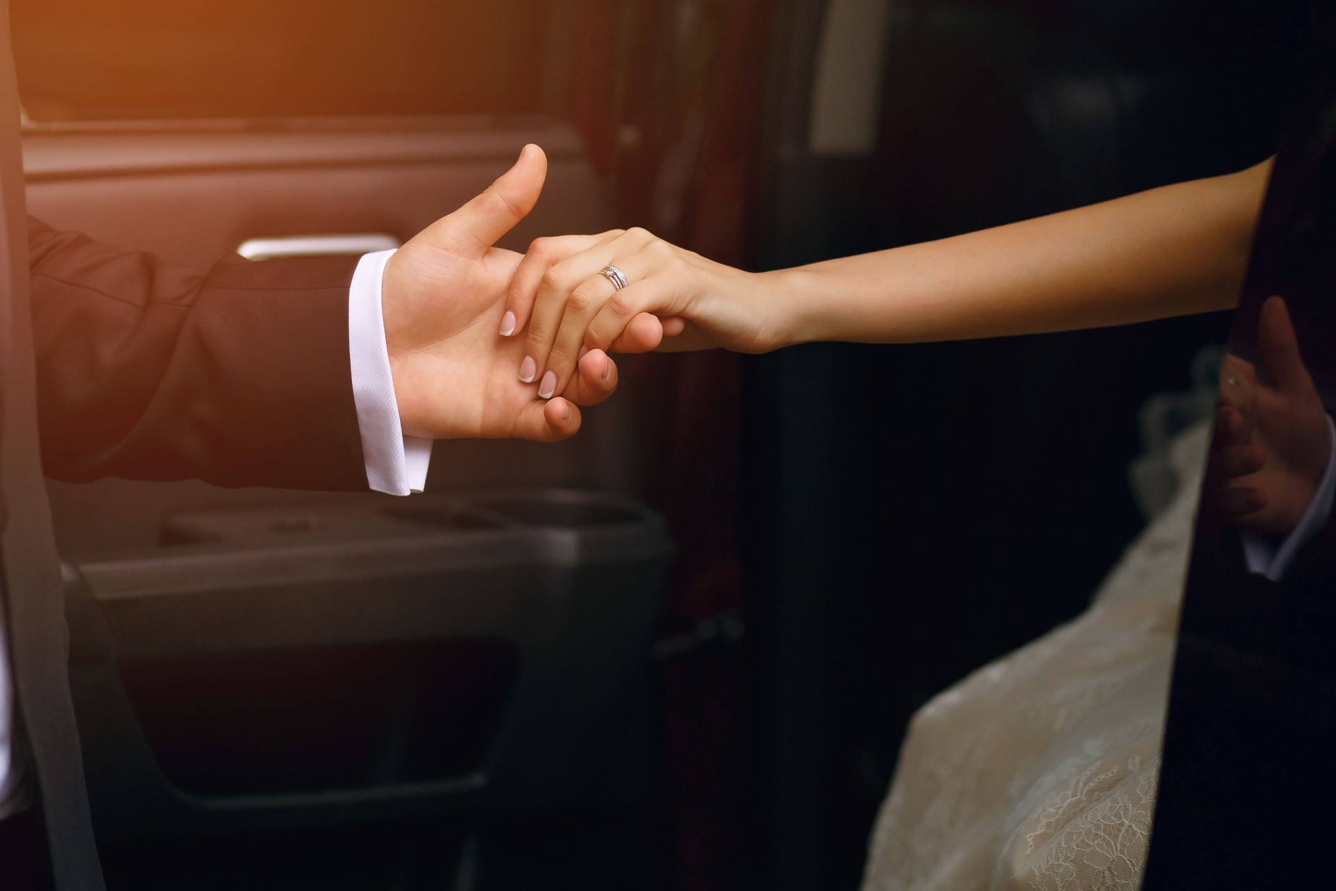 Bride and groom, a man holds out his hand to a woman when she gets out of the car